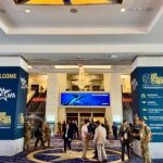 Attendees gather inside the Air, Space & Cyber Conference venue, with event signage and exhibit directions displayed in the main lobby.
