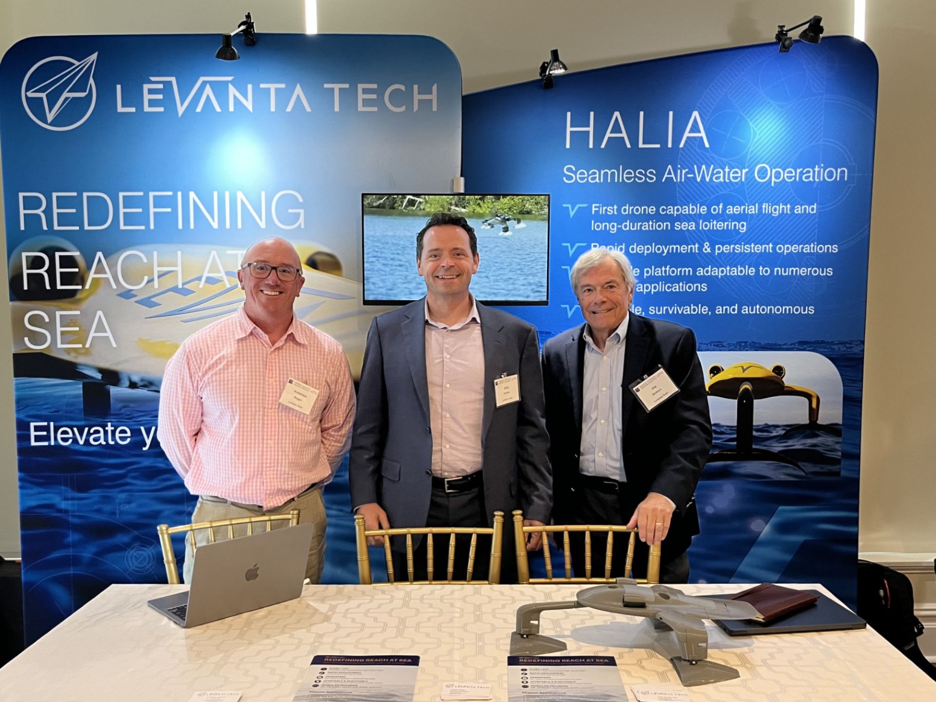 LeVanta Tech team members standing at a conference booth in front of HALIA float-and-fly drone display panels.